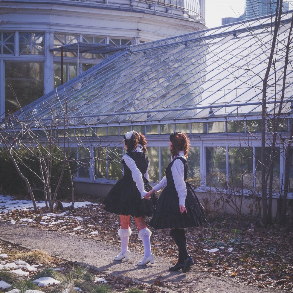 two gothic lolitas walking towards a greenhouse